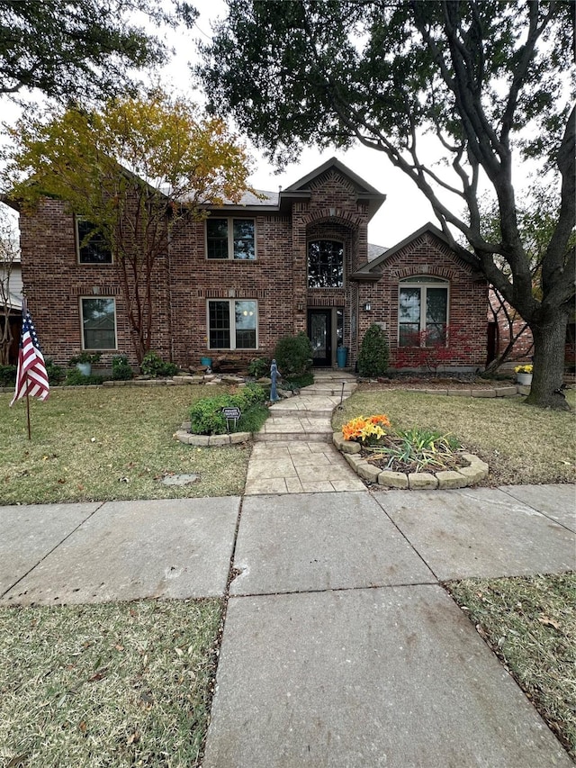 traditional-style house featuring brick siding and a front yard