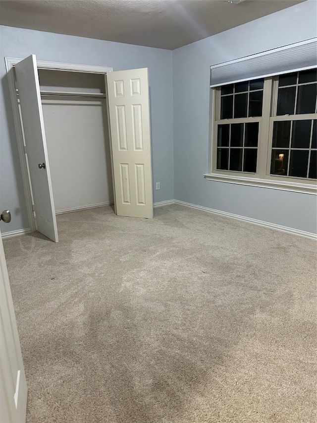 unfurnished bedroom with a closet, baseboards, and carpet