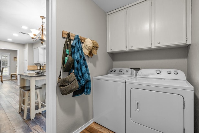 laundry room featuring cabinet space, light wood finished floors, visible vents, washer and dryer, and a notable chandelier