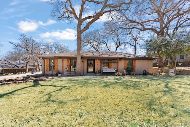 back of property with a porch, brick siding, and a yard