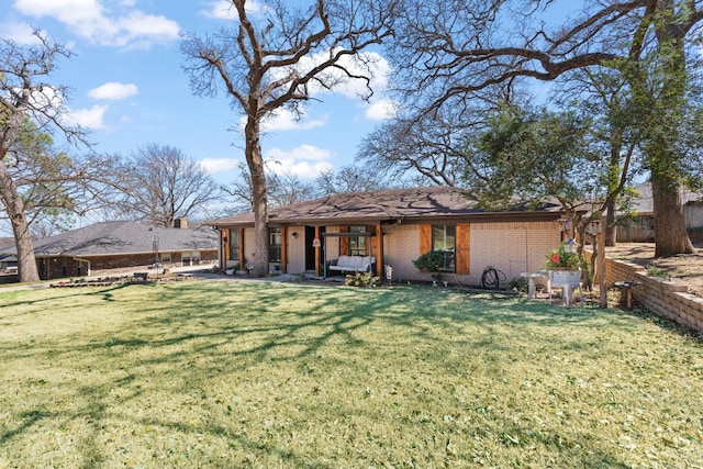 back of property featuring brick siding, a lawn, and fence