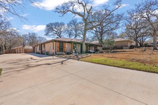 ranch-style home with an outbuilding, concrete driveway, brick siding, and fence