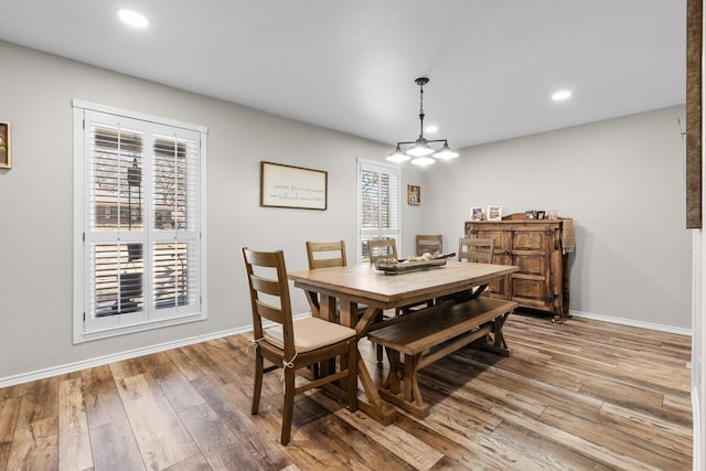 dining area with light wood-type flooring, baseboards, and an inviting chandelier