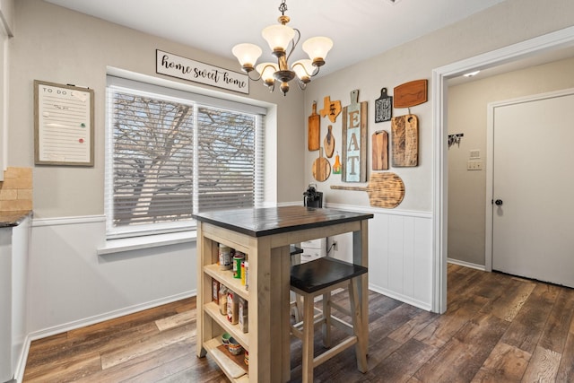 dining room with an inviting chandelier, dark wood finished floors, and wainscoting