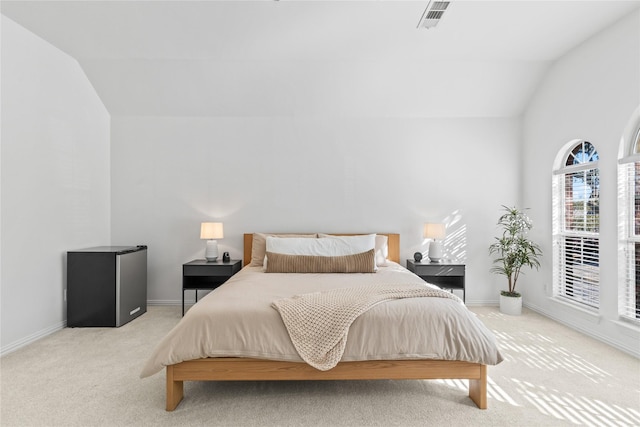 bedroom with light colored carpet, lofted ceiling, visible vents, and baseboards