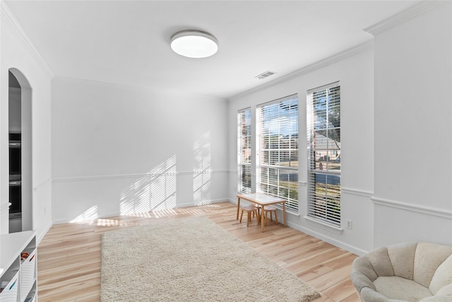 sitting room with crown molding, visible vents, arched walkways, and wood finished floors