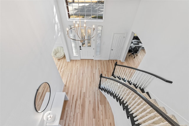 foyer with stairs, wood finished floors, a towering ceiling, and baseboards