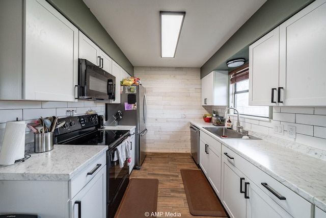 kitchen with dark wood finished floors, decorative backsplash, white cabinets, a sink, and black appliances