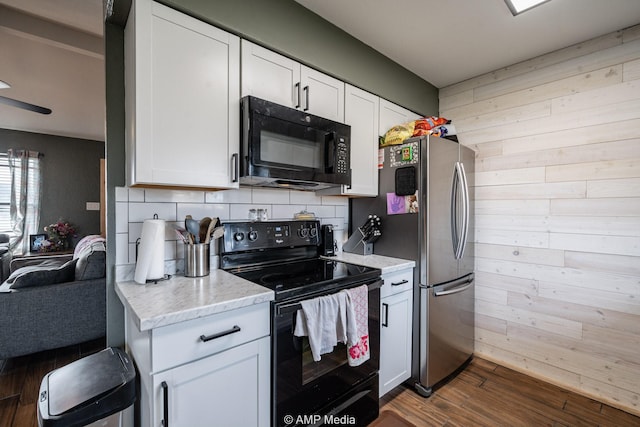 kitchen featuring black appliances, decorative backsplash, dark wood-style flooring, and wood walls