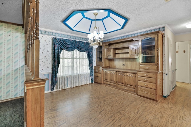 dining space featuring a textured ceiling, light wood-style flooring, a notable chandelier, crown molding, and wallpapered walls