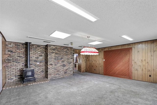 unfurnished living room featuring a wood stove, carpet, visible vents, and a textured ceiling