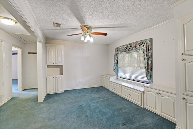 interior space with a textured ceiling, visible vents, dark colored carpet, and crown molding