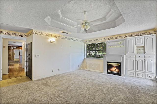 unfurnished living room featuring visible vents, carpet, a tray ceiling, a textured ceiling, and crown molding