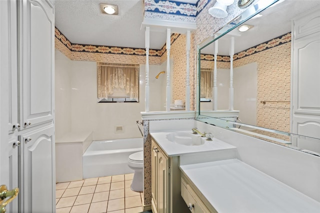 bathroom with a textured ceiling, toilet, vanity, tile patterned floors, and wallpapered walls