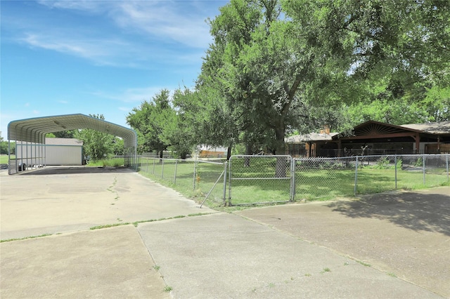 view of yard with a carport, a gate, fence, and concrete driveway