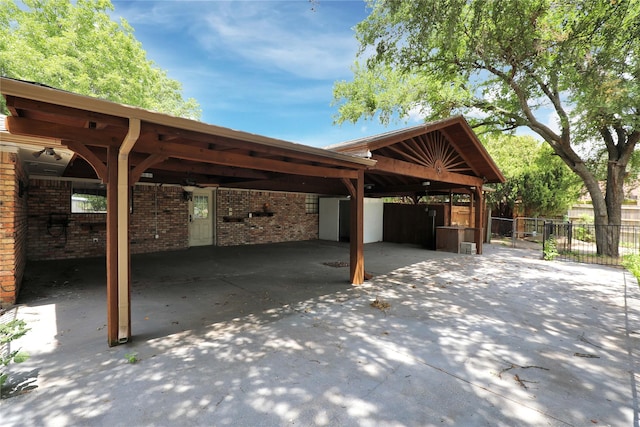 view of car parking featuring driveway, fence, and a carport