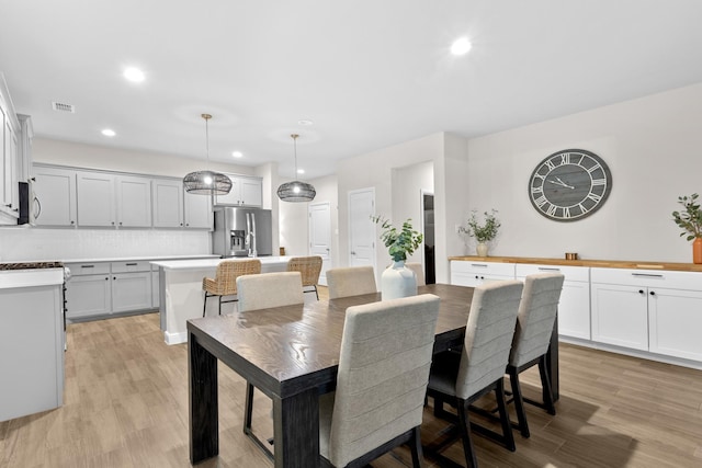 dining space with light wood-style flooring, visible vents, and recessed lighting