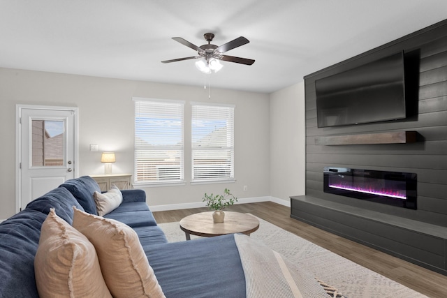 living room featuring a glass covered fireplace, wood finished floors, and baseboards