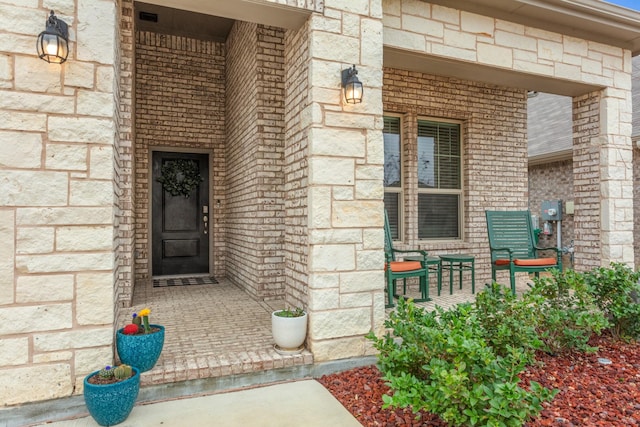 entrance to property featuring covered porch and brick siding