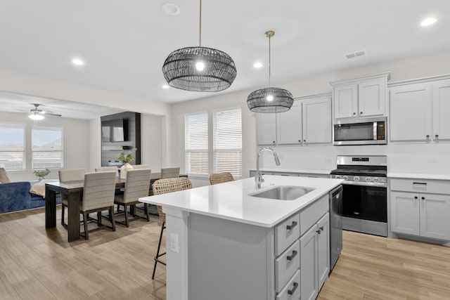 kitchen featuring light countertops, stainless steel appliances, a sink, and open floor plan