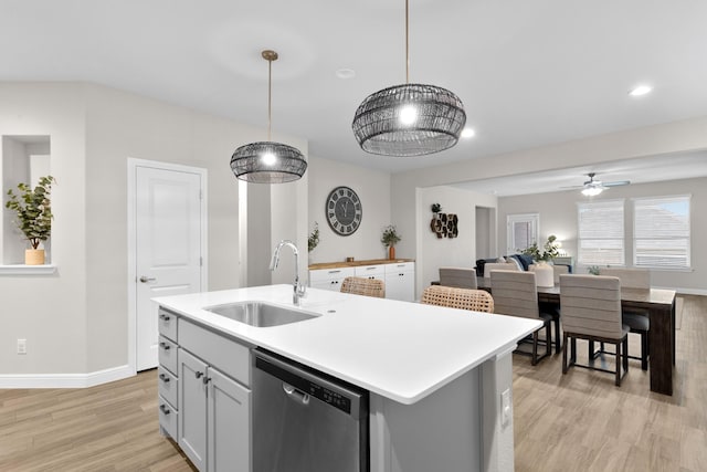 kitchen with a center island with sink, light countertops, a sink, light wood-type flooring, and dishwasher