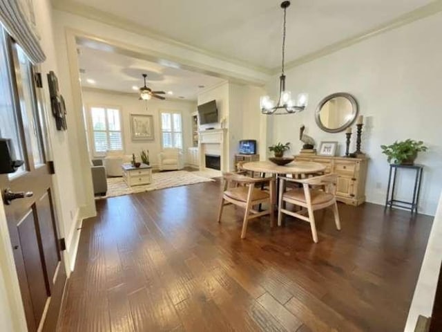 1933 Woodberry Ave, Shreveport, LA 71106 - dining space with dark wood-type flooring, ornamental molding, ceiling fan with notable chandelier, and a fireplace