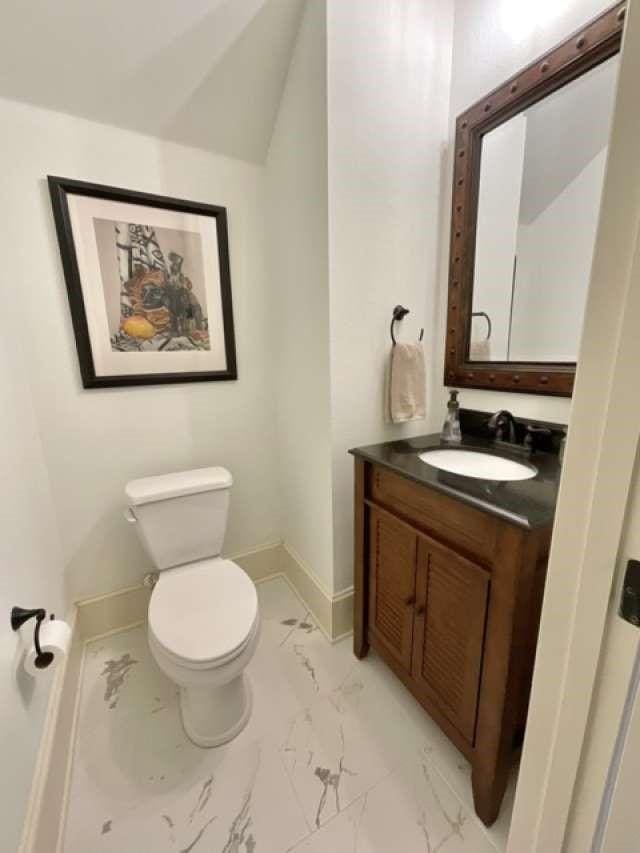 bathroom with marble finish floor, vanity, toilet, and baseboards