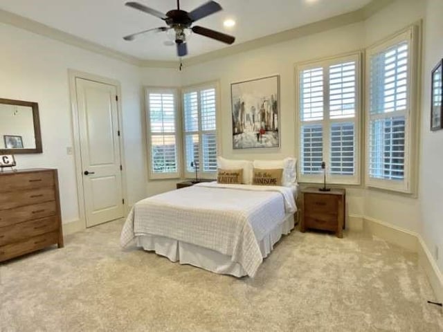 bedroom with baseboards, crown molding, a ceiling fan, and light colored carpet