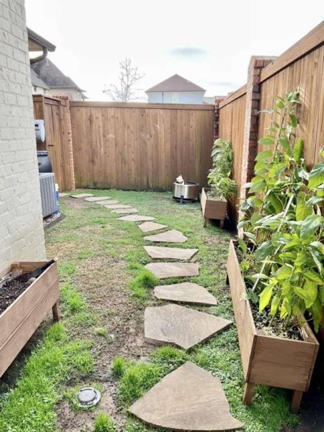 view of yard with a fenced backyard, a vegetable garden, and cooling unit