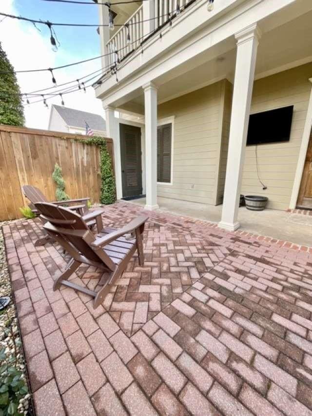 view of patio featuring outdoor dining area, fence, and a balcony