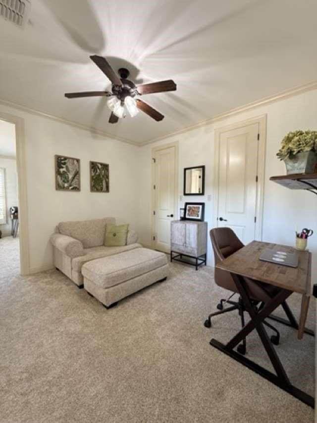 home office with visible vents, ornamental molding, a ceiling fan, and light colored carpet