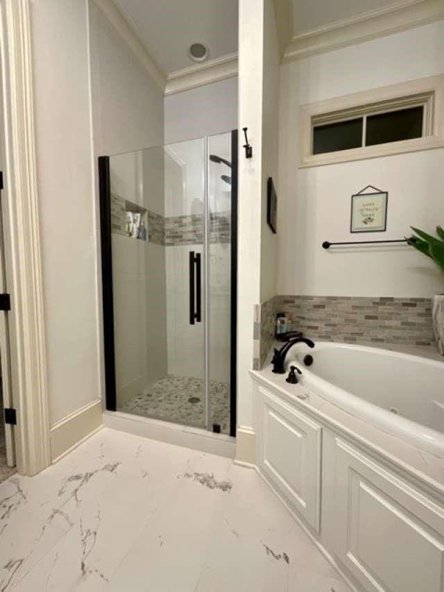 full bathroom featuring marble finish floor, a stall shower, a bath, and crown molding