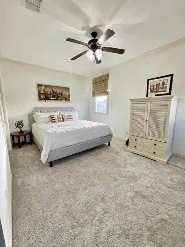 carpeted bedroom featuring ceiling fan and visible vents