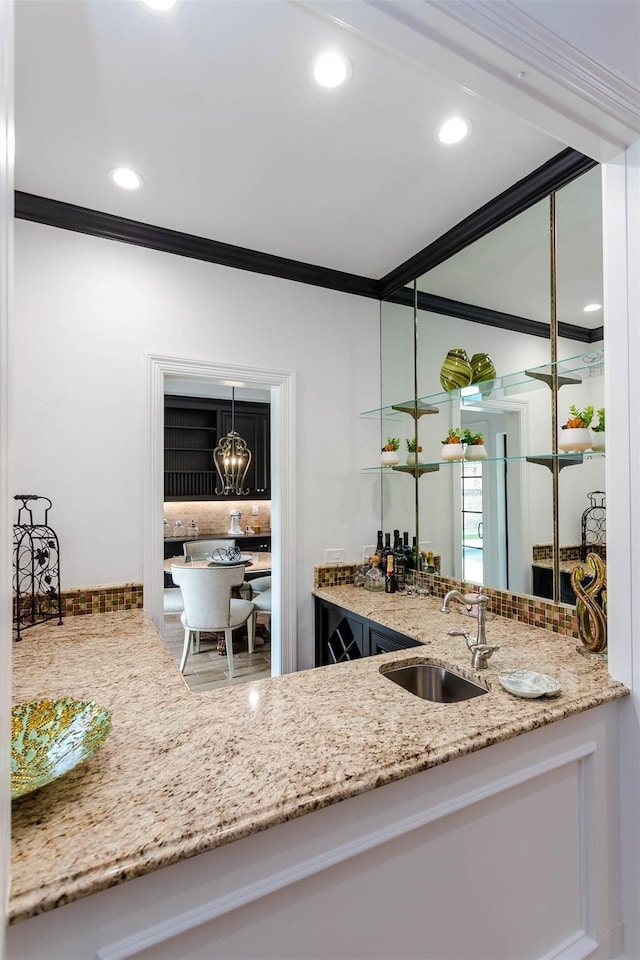 kitchen with light stone countertops, crown molding, a sink, and recessed lighting