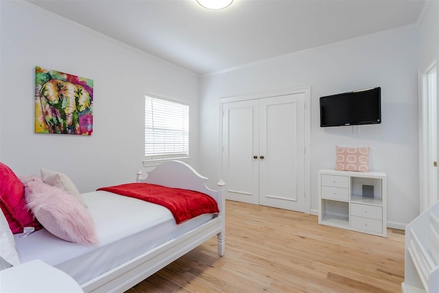 bedroom featuring ornamental molding, a closet, and light wood-type flooring