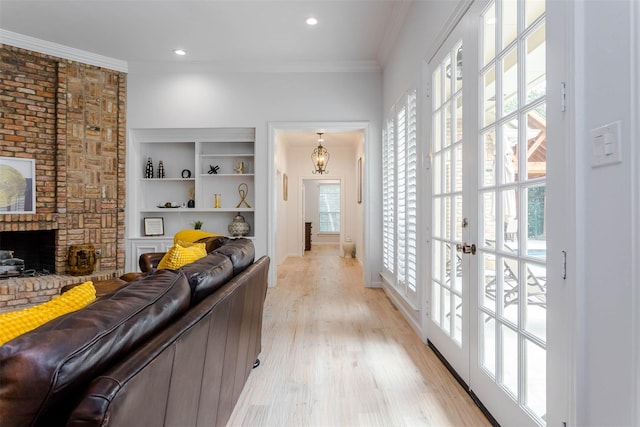 living area featuring plenty of natural light, a brick fireplace, light wood-type flooring, and crown molding