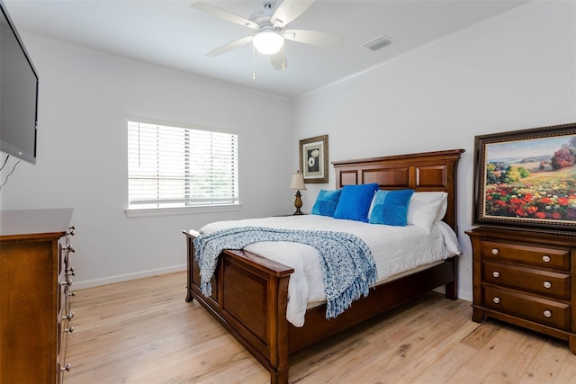 bedroom with light wood-style floors, visible vents, and crown molding