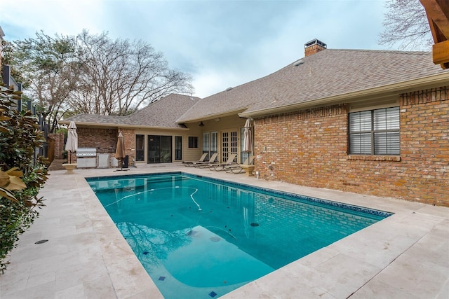 pool featuring exterior kitchen, french doors, a patio, and area for grilling