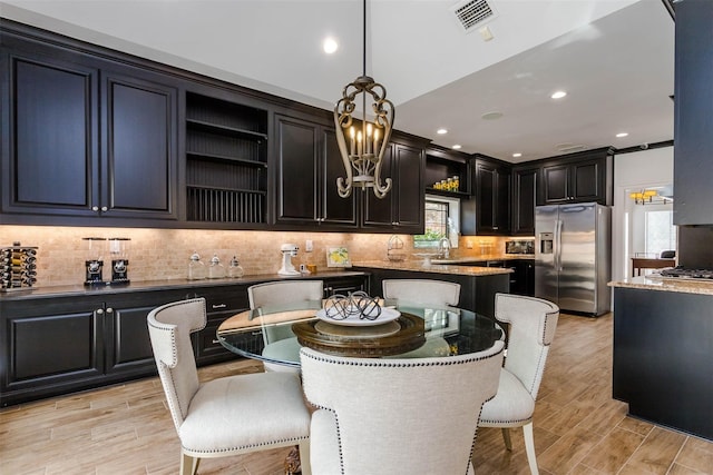 kitchen with pendant lighting, stainless steel appliances, visible vents, decorative backsplash, and a kitchen bar