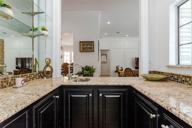 kitchen with a wealth of natural light, dark cabinetry, a sink, and decorative backsplash