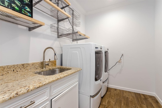 laundry room featuring crown molding, washing machine and dryer, a sink, wood finished floors, and baseboards