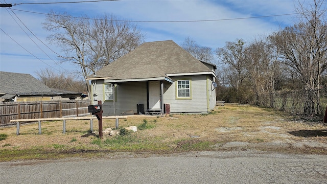 bungalow-style home featuring fence and roof with shingles