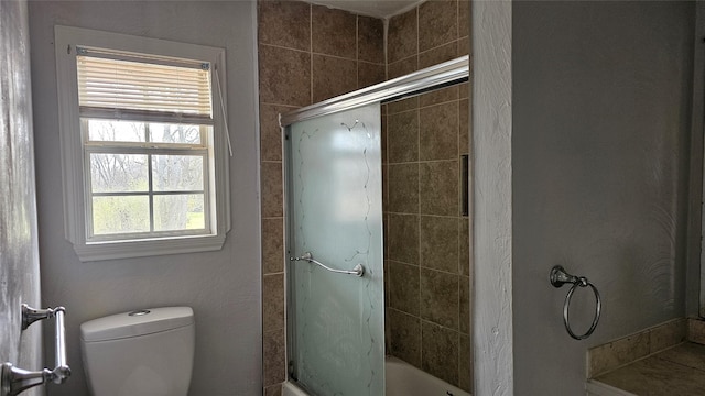 full bathroom with bath / shower combo with glass door and toilet