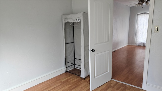 interior space featuring a ceiling fan, light wood-type flooring, and baseboards