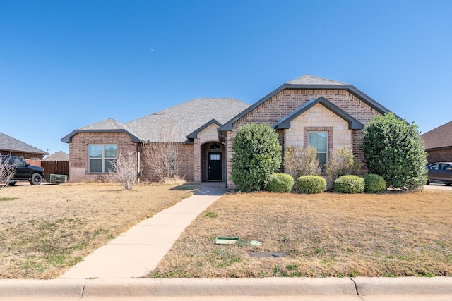 view of front of property featuring stone siding, a front yard, fence, and brick siding