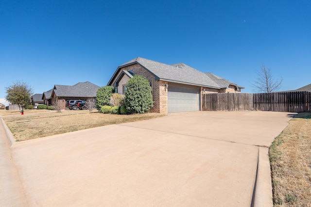 view of property exterior featuring driveway, an attached garage, fence, and brick siding