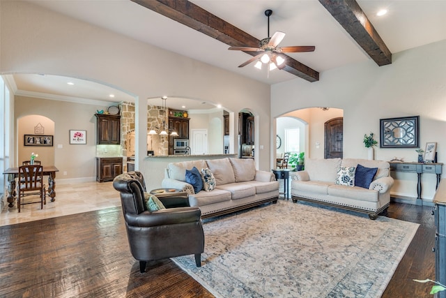 living area featuring baseboards, arched walkways, beamed ceiling, wood finished floors, and crown molding