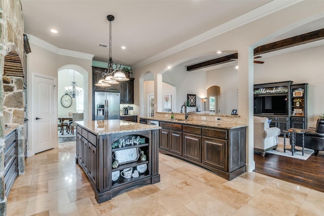 kitchen with light stone countertops, stainless steel fridge, arched walkways, and dark brown cabinets