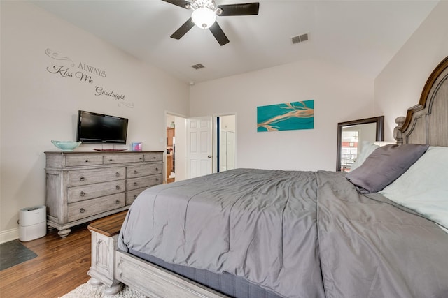 bedroom featuring a ceiling fan, visible vents, vaulted ceiling, and wood finished floors