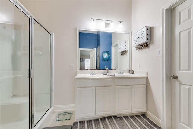 full bathroom featuring double vanity, a stall shower, and a sink